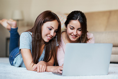 Buy stock photo Two teenage girls sharing a laptop on the floor at home