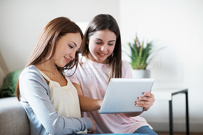 Buy stock photo Two sisters looking at something on their digital tablet early in the morning