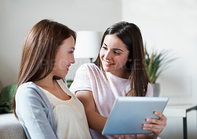 Buy stock photo Two teenage sisters talking while holding a digital tablet