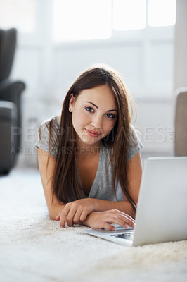 Buy stock photo Portrait of a gorgeous teenage girl working on her laptop while lying on her living room floor