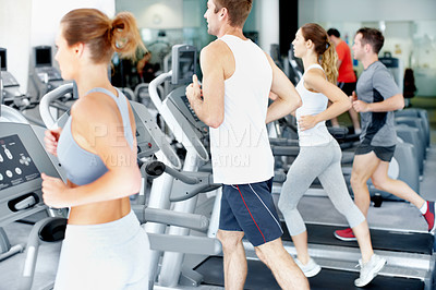 Buy stock photo View of a row of fit young people running on treadmills at the gym