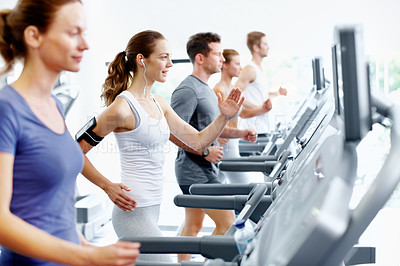 Buy stock photo Healthy young woman running on a treadmill at the gym