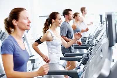 Buy stock photo Fit young woman running on a treadmill at the gym
