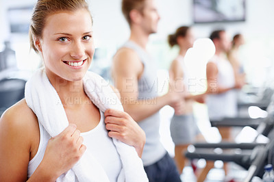 Buy stock photo Happy young woman standing alongside a row of treadmills at the gym