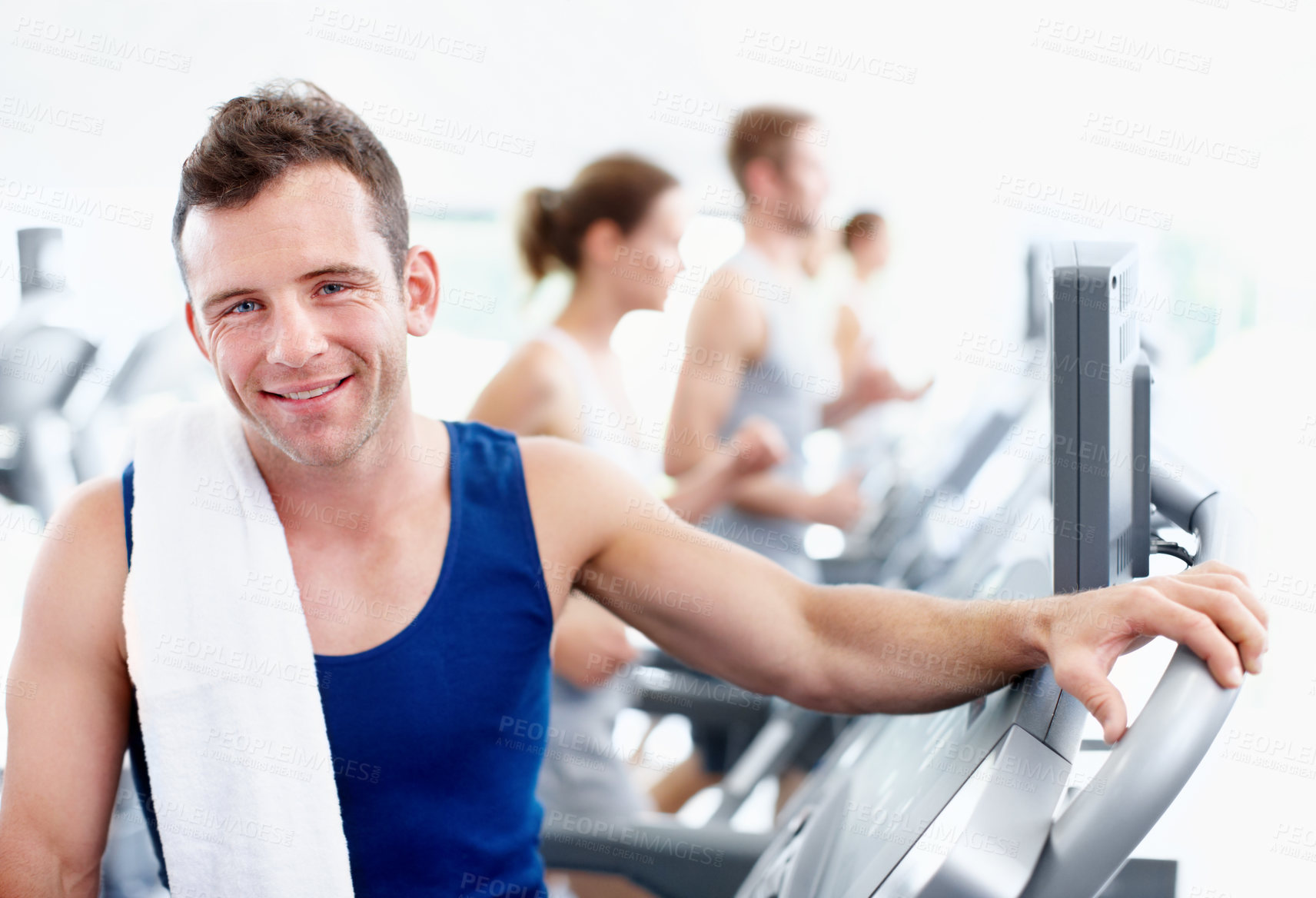 Buy stock photo Healthy young man standing alongside a treadmill at the gym
