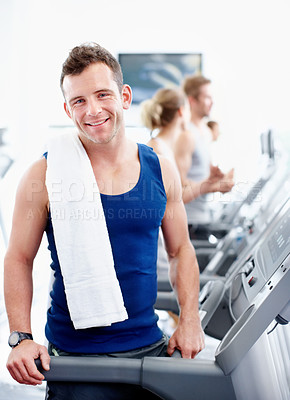 Buy stock photo Health-conscious young man standing alongside a treadmill at the gym