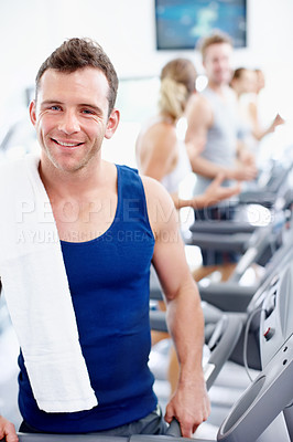 Buy stock photo Athletic young man standing alongside a treadmill at the gym