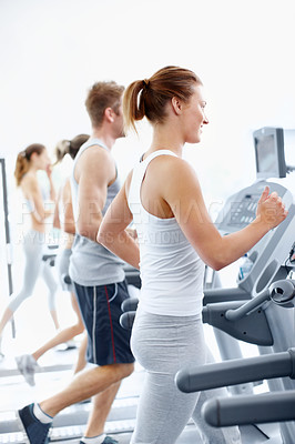 Buy stock photo Row of fit young people using equipment at the gym