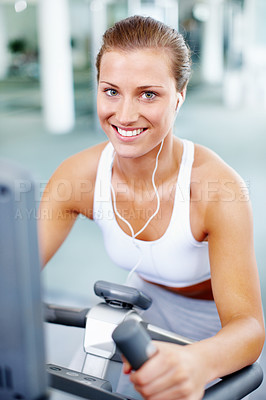 Buy stock photo Smiling woman using an exercise bicycle while listening to music - portrait