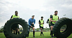 Fitness, coach and team with tire on field, strength challenge and training for sport competition. Coaching, trainer or rugby players with exercise for muscle development, active men or weightlifting