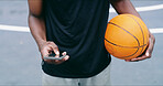 Man, hands and basketball on court with phone, fitness app and research training tips for practice. Person, outdoor and scroll with tech for sports website, wellness or text message from social media