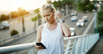 Buy stock photo Fitness, online and woman with earphones on bridge, texting and listening to music with subscription. Serious, athlete and person with phone for chat, wellness and streaming audio with tech in city