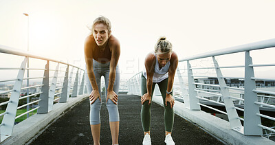 Buy stock photo Bridge, fitness and running with tired women in city together for cardio, training or workout. Break, breathing and recovery with exhausted friends in urban town for fatigue, health or wellness