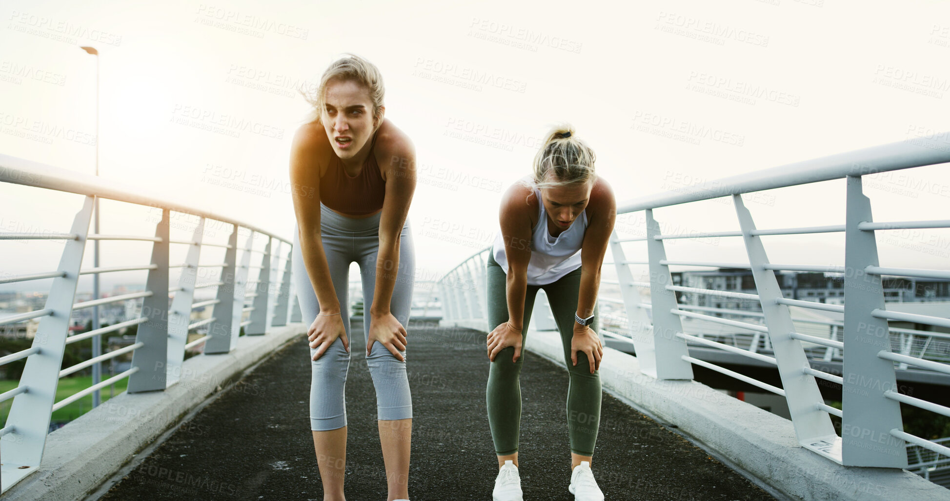 Buy stock photo Bridge, fitness and running with tired women in city together for cardio, training or workout. Break, breathing and recovery with exhausted friends in urban town for fatigue, health or wellness