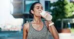 Woman, drinking water and rest in city for fitness with hydration, detox or electrolytes with wellness. Person, runner and bottle for liquid, break and outdoor on street with exercise in urban town
