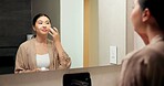 Bathroom, mirror and woman with cream for skincare, grooming or anti aging cosmetic for healthy skin. Reflection, check and Asian person with smile, hygiene and self care with moisturizer in house