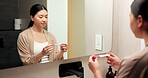 Woman, pregnancy test and results in bathroom, home and check for fertility with thinking in morning. Asian person, monitor or stick for outcome, IVF and stress at mirror with reflection in house