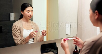 Buy stock photo Woman, pregnancy test and results in bathroom, home and check for fertility with thinking in morning. Asian person, monitor or stick for outcome, IVF and waiting at mirror with reflection in house