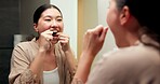 Dental care, mirror and woman flossing teeth in bathroom at house for hygiene routine in morning. Happy, wellness and Asian female person with cleaning mouth treatment for fresh breath in apartment.