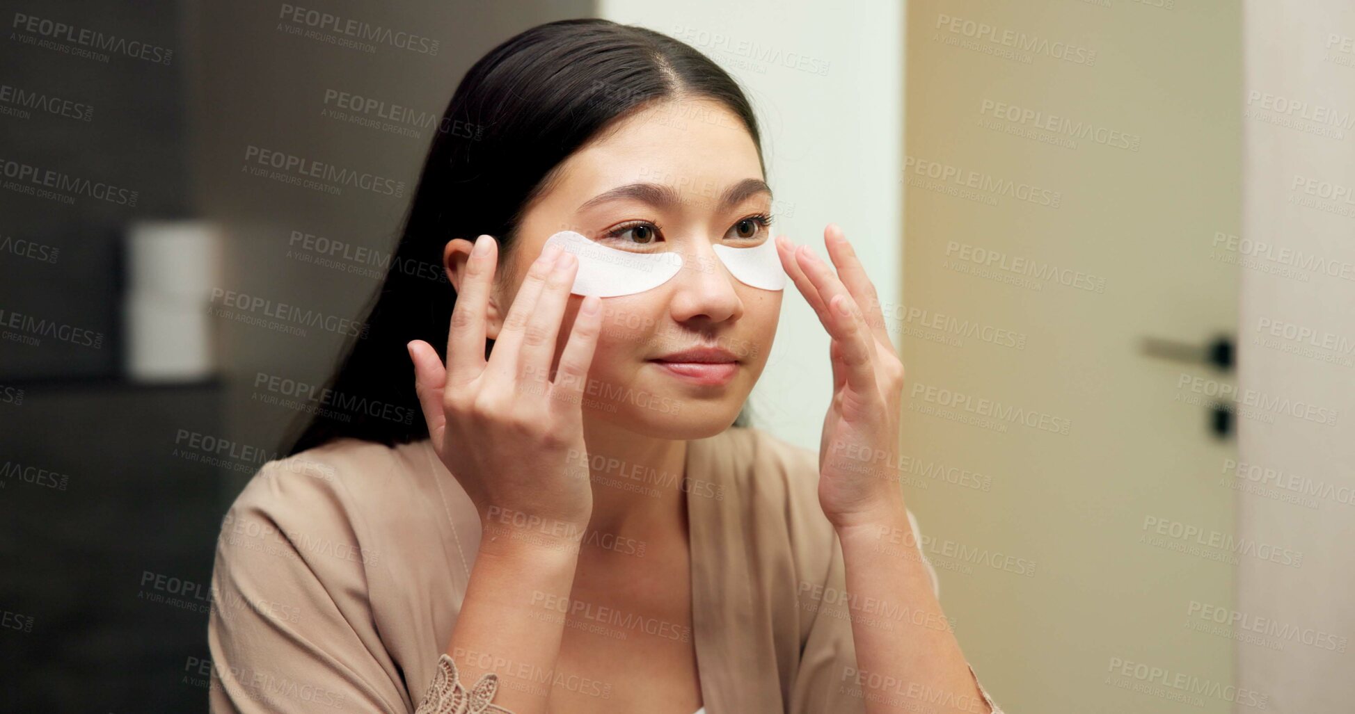 Buy stock photo Bathroom, mirror and woman with eye mask for skincare, hydration or self care routine with cosmetics. Reflection, home and Asian person with smile, dermatology and reducing puffiness with patches
