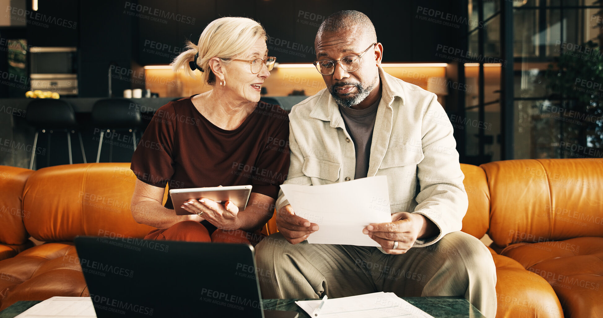 Buy stock photo Interracial couple, tablet and reading with documents in home for finance, bills or investment. Mature man, woman and paperwork with tech for financial planning, budget expenses or invoices together