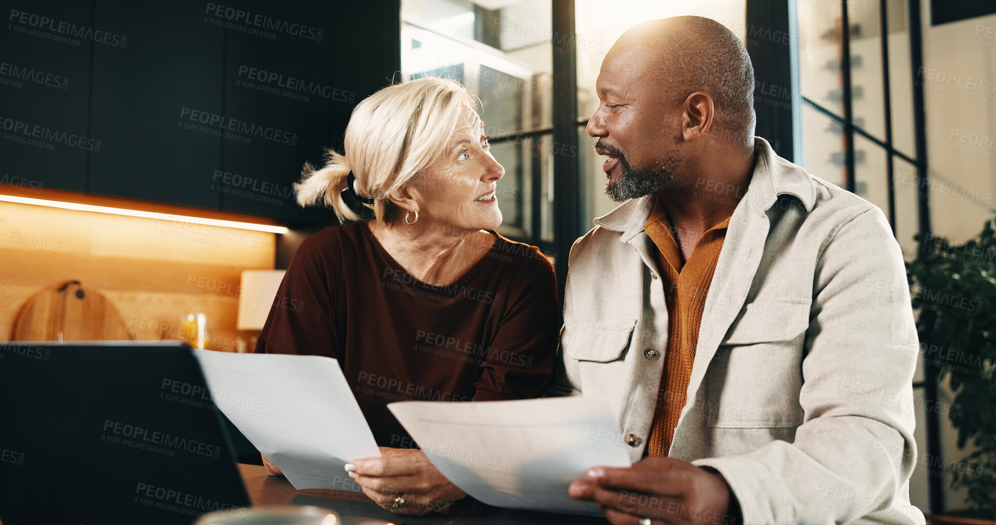 Buy stock photo Interracial couple, laptop and discussion with paperwork in home for finance, bills or investment. Mature man, woman and documents with tech for financial planning, budget expenses or invoices