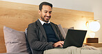 Business, man and relax in bedroom with laptop, social media and browsing website to unwind. Smile, corporate and male person at house with tech, streaming movies and watching video for weekend break
