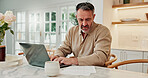 Man, laptop and home with documents for finance, budget planning or asset management in kitchen. Mature, male person or checking invoices with paperwork or computer for financial expenses in house