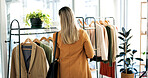 Back, clothes and woman in boutique, choice and shopping with retail therapy, fabric quality and fashion. Customer, luxury design and person in store, discount deal and sale for product and textile