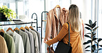 Back, clothes and woman in store, choice and shopping with retail therapy, options and fashion. Customer, luxury design and person in boutique, discount deal and sale for product and rack with fabric