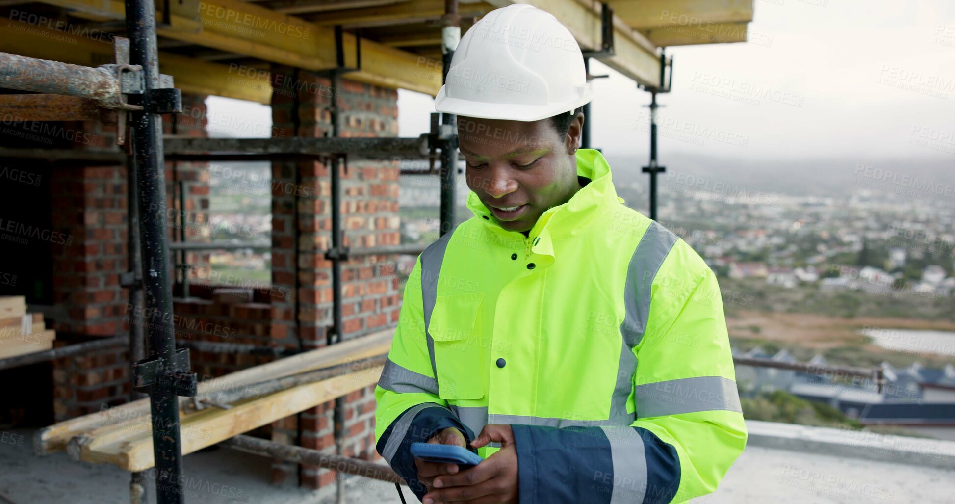 Buy stock photo Black man, typing and construction worker on site with phone for email feedback on renovation. Cellphone, smile and male civil engineer with texting for approval on building, maintenance or repairs.