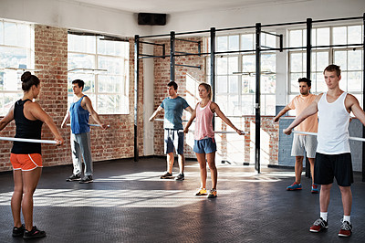 Buy stock photo Shot of a group of people doing a fitness class with bars