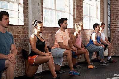 Buy stock photo Shot of a group of people lined up against the wall on one knee in a fitness class