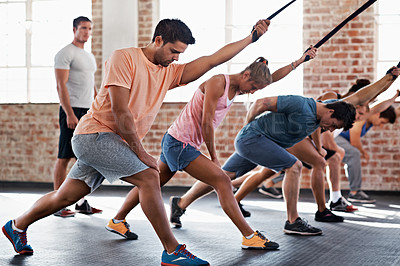 Buy stock photo Shot of a group of people using resistance bands in a crossfit class while an instructor looks on