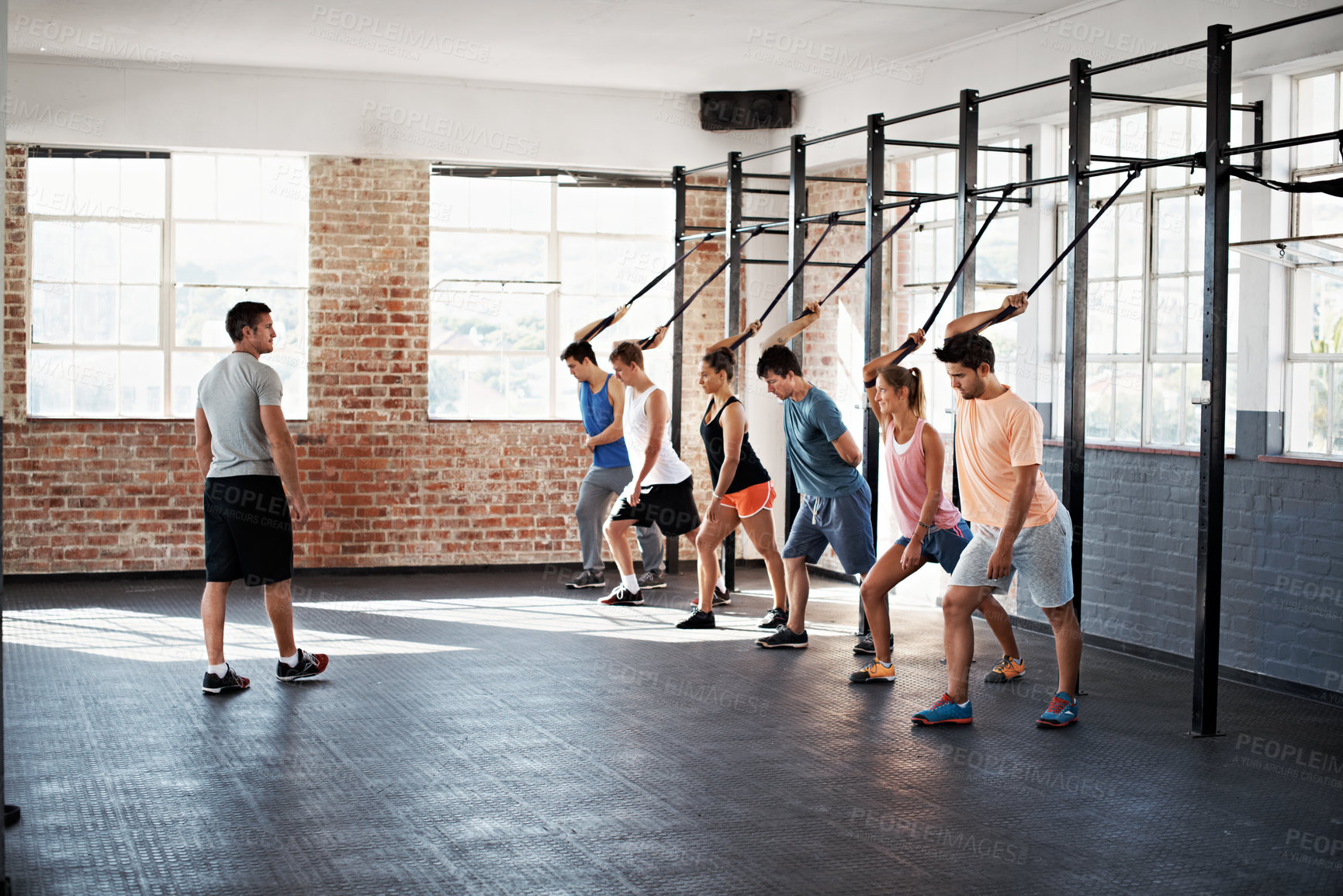 Buy stock photo Trainer, people and stretching at gym with rope, fitness and resistance exercise for wellness. Man, coaching and group at facility with rig machine, strength training and challenge for power workout