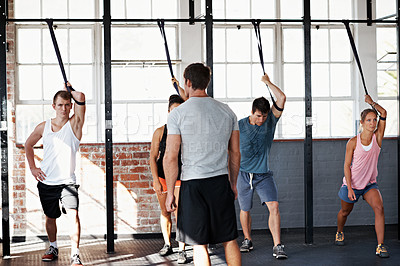 Buy stock photo Shot of a group of people using resistance bands in a crossfit class while an instructor looks on