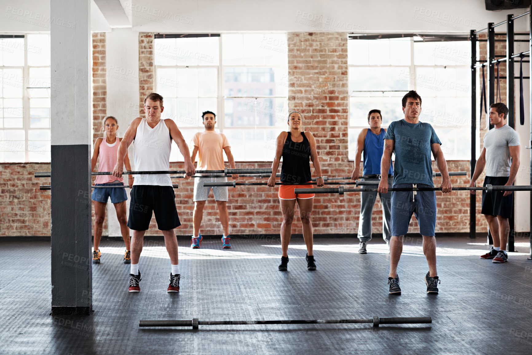 Buy stock photo People, instructor and barbell at gym for fitness, exercise and challenge for strength training. Group, session and trainer with equipment for weightlifting, endurance workout and resilience wellness