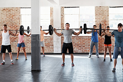 Buy stock photo Shot of a group of people lifting barbell weights in a fitness class