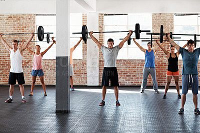 Buy stock photo Shot of a group of people lifting barbell weights in a fitness class