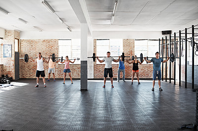 Buy stock photo Shot of a group of people lifting barbell weights in a fitness class