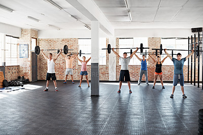 Buy stock photo Shot of a group of people lifting barbell weights in a fitness class