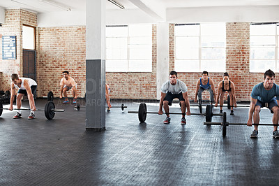 Buy stock photo Shot of a group of people preparing to lift barbell weights in a fitness class