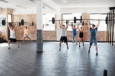 Buy stock photo Shot of a group of people lifting barbell weights in a fitness class