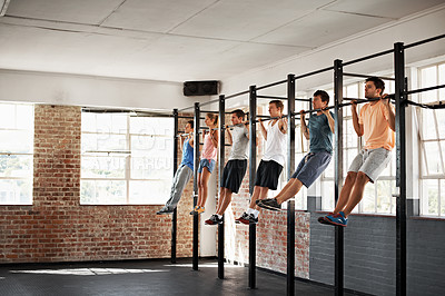 Buy stock photo Shot of a group of people doing pullups in a row in a fitness class