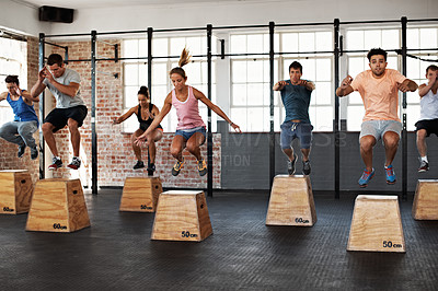 Buy stock photo Shot of a group of people jumping onto boxes in a crossfit class