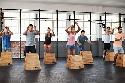 Buy stock photo Shot of a group of people jumping onto boxes in a crossfit class