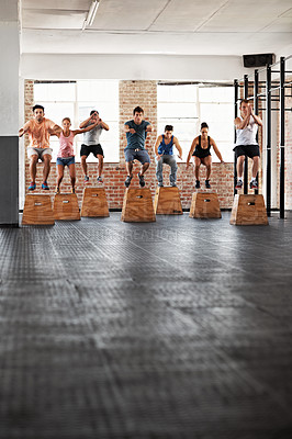 Buy stock photo Shot of a group of people jumping onto boxes in a crossfit class