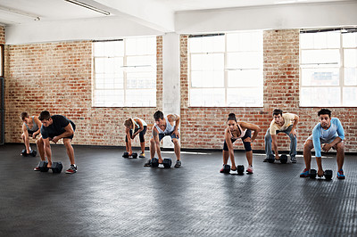 Buy stock photo Shot of a group of people preparing to lift dumbbells in a fitness class
