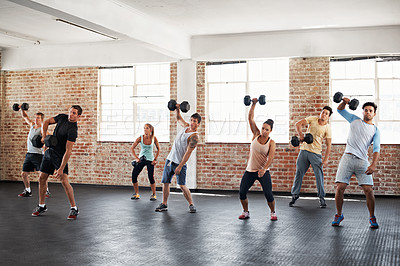 Buy stock photo Shot of a group of people lifting dumbbells in a fitness class