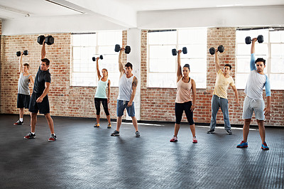 Buy stock photo Shot of a group of people lifting dumbbells in a fitness class
